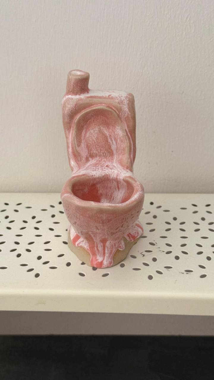 Kleine Skulptur in Form einer Toilette mit rosa und weiß marmorierter Glasur